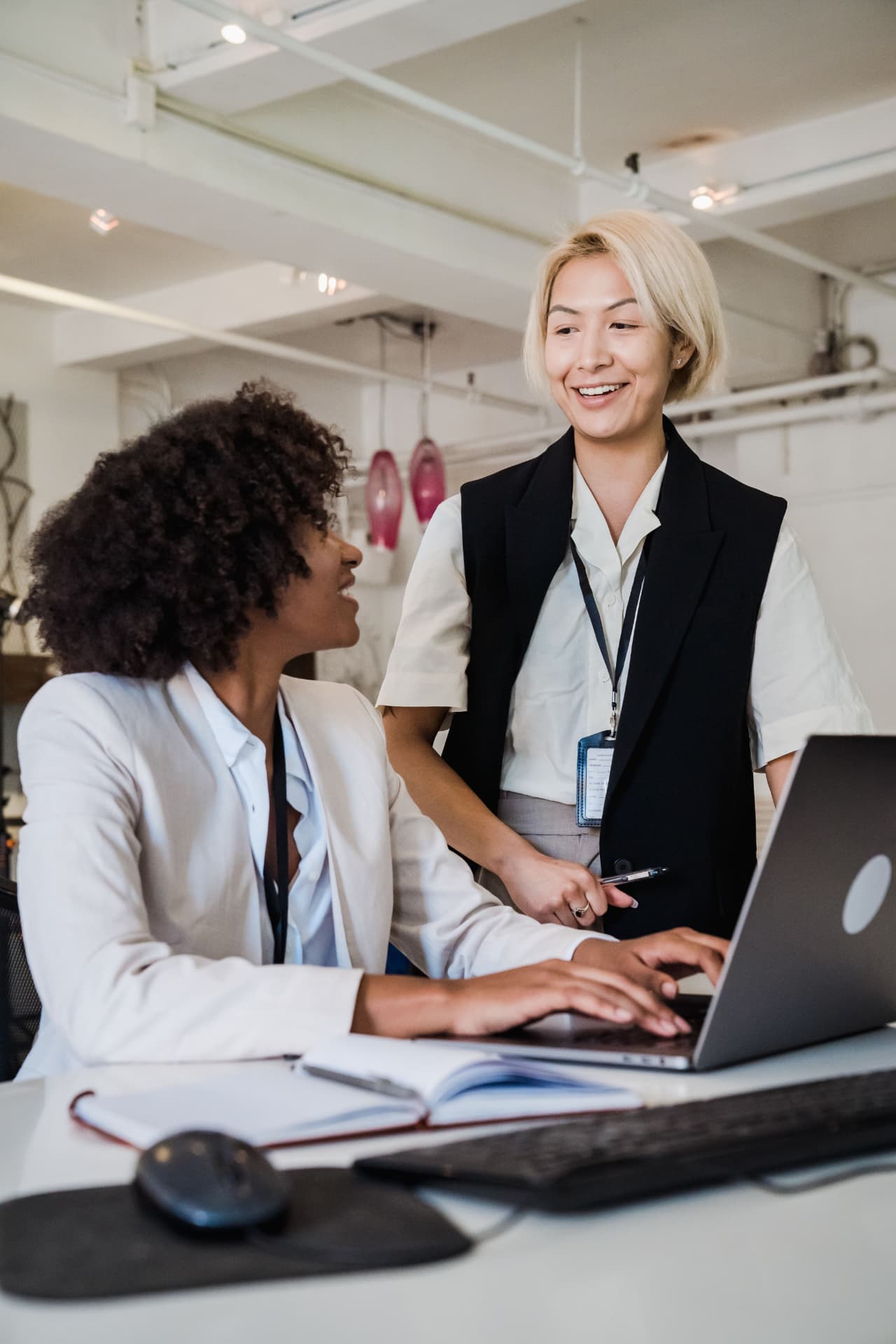 Two colleagues reviewing work together at a laptop in a bright office